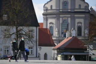 Two persons walk on an empty square at the Graciousness Chapel in Altoetting, Germany, March 31, 2020 as the spread of the coronavirus disease (COVID-19) continues. REUTERS/Andreas Gebert
