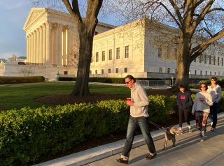 A family walk their dog past the U.S. Supreme Court building at sunset during the outbreak of the coronavirus disease (COVID-19), as personal exercise is exempted from the city-wide stay at home orders in Washington, U.S. April 3, 2020. REUTERS/Jonathan E