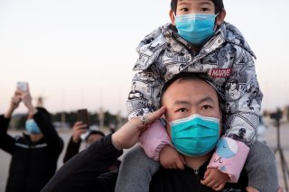 A man wearing a face mask salutes during a ceremony where the Chinese national flag is positioned at half-mast, at Tiananmen Square in Beijing as China holds a national mourning for those who died of the coronavirus disease (COVID-19), on the Qingming tom