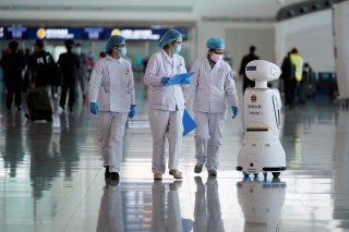 Medical workers walk by a police robot at the Wuhan Tianhe International Airport after travel restrictions to leave Wuhan, the capital of Hubei province and China's epicentre of the novel coronavirus disease (COVID-19) outbreak, were lifted, April 8, 2020