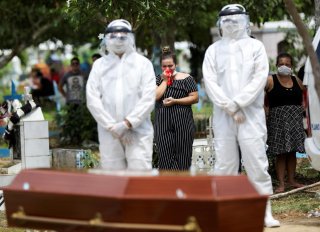 Relatives of 68-years-old Natalina Cardoso Bandeira, who passed away due to coronavirus disease (COVID-19), react during her burial at the Parque Taruma cemetery in Manaus, Brazil, April 10, 2020. REUTERS/Bruno Kelly