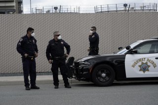 California Highway Patrol officers wearing protective masks wait at a car rally protesting the alleged pepper-spraying of immigrant women detained at the Otay Mesa Detention Center, a ICE (Immigrations & Customs Enforcement) federal detention center priva