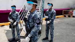 Members of the Philippine Coast Guard wearing protective masks hold their weapons with gloves outside a passenger vessel turned into a temporary quarantine facility for Filipino seafarers to contain the coronavirus disease (COVID-19) in Manila, Philippine