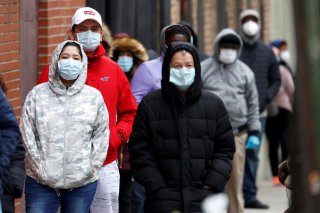 People wearing protective face masks wait in line outside NYC Health + Hospitals/Gotham Health Morrisania neighborhood health center, one of New York City's new walk-in COVID-19 testing centers, during the outbreak of the coronavirus disease (COVID-19) in