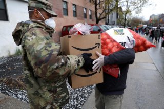 A U.S. Army National Guard soldier gives food to a man at a curbside food pantry for needy residents during the outbreak of the coronavirus disease (COVID-19) in the Brooklyn borough of New York City, New York, U.S., April 24, 2020. REUTERS/Mike Segar