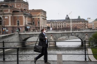 A man wearing a protective mask walks past the Royal Swedish Opera, amid the coronavirus disease (COVID-19) outbreak in Stockholm, Sweden, April 27, 2020. Fredrik Sandberg/TT News Agency/via REUTERS