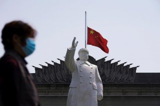 The Chinese national flag flies at half-mast behind a statue of late Chinese chairman Mao Zedong in Wuhan, Hubei province, as China holds a national mourning for those who died of the coronavirus disease (COVID-19), on the Qingming tomb-sweeping festival,