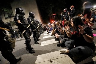 Protesters sit in the street facing a line of riot policemen during nationwide unrest following the death in Minneapolis police custody of George Floyd, in Raleigh, North Carolina, U.S. May 31, 2020. REUTERS/Jonathan Drake