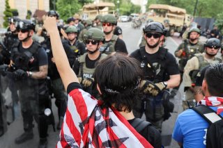 Demonstrators stand in front of law enforcement officers during a protest against the death in Minneapolis police custody of George Floyd, near the White House in Washington, U.S., June 3, 2020. REUTERS/Jonathan Ernst