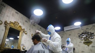 Barbers wearing protective suits and face masks provide hair cut service to the customers inside a salon amid the coronavirus disease (COVID-19) outbreak, in Dhaka, Bangladesh June 16, 2020. REUTERS/Mohammad Ponir Hossain