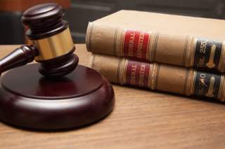 Judge's gavel in a courtroom, stack of law books.