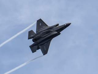 An F-35B Lightning II, attached to the “Avengers” of Marine Fighter Attack Squadron (VMFA) 211, flies over Wasp-class amphibious assault ship USS Essex