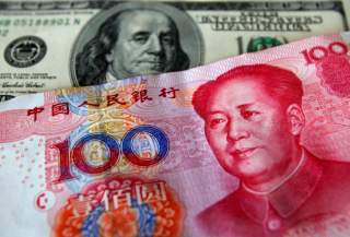 FILE PHOTO: A yuan banknote is displayed next to a U.S. dollar banknote (back) for the photographer at a money changer inside the Taoyuan International Airport March 18, 2010. REUTERS/Nicky Loh/File Photo