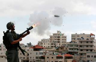 An Israeli border police officer fires tear gas towards Palestinian stone-throwers in East Jerusalem neighbourhood of Issawiya March 16, 2010. Dozens of Palestinian stone-throwers clashed with Israeli police in East Jerusalem on Tuesday on a 