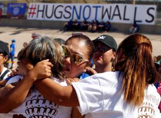 Mexicans (white shirts), who live in Mexico, hug relatives (blue shirts), who live in the U.S., during the Hugs Not Walls event on the border between Ciudad Juarez, Mexico and El Paso, U.S., May 12, 2018. REUTERS/Jose Luis Gonzalez