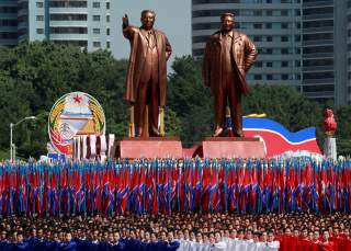 People carry flags in front of statues of North Korea founder Kim Il Sung (L) and late leader Kim Jong Il during a military parade marking the 70th anniversary of North Korea's foundation in Pyongyang, North Korea, September 9, 2018. REUTERS/Danish Siddiq