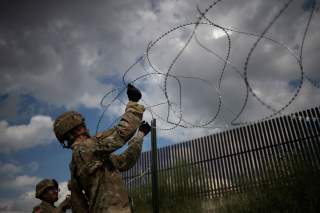 The border wall is seen in the background as U.S. Army soldiers install concertina wire along the United States - Mexico border in Hidalgo, Texas, U.S., November 8, 2018. Picture taken on November 8, 2018. REUTERS/Adrees Latif