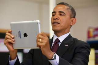 U.S. President Barack Obama holds up an Apple iPad during a visit to Buck Lodge Middle School in Adelphi, Maryland February 4, 2014.