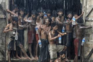 Migrants, who were found at sea on a boat, collect rainwater during a heavy rain fall at a temporary refuge camp near Kanyin Chaung jetty, outside Maungdaw township, northern Rakhine state, Myanmar June 4, 2015. Myanmar on Wednesday landed the boat with 7