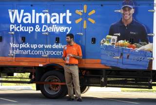 A Wal-Mart Pickup-Grocery employee waits next to a truck at a test store in Bentonville, Arkansas June 4, 2015. REUTERS/Rick Wilking
