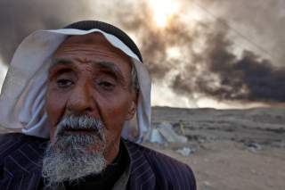 A man returns to his village after it was liberated from Islamic State militants, south of Mosul in Qayyara, Iraq, October 22, 2016. The fumes in the background are from oil wells that were set ablaze by Islamic State militants. REUTERS/Alaa Al-Marjani TP