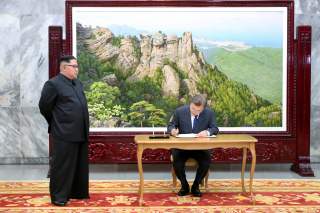 South Korean President Moon Jae-in signs a guestbook as North Korean leader Kim Jong Un looks on before their summit at the truce village of Panmunjom, North Korea, in this handout picture provided by the Presidential Blue House on May 26, 2018. Picture t