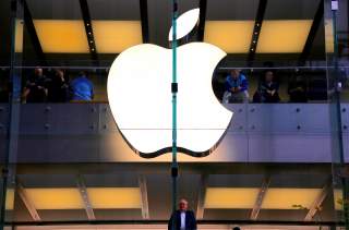A customer stands underneath an illuminated Apple logo as he looks out the window of the Apple store located in central Sydney, Australia, May 28, 2018.