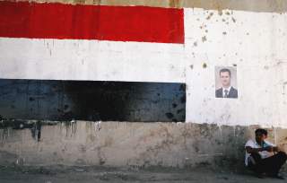 A man sits near a poster of Syrian President Bashar al Assad during the re-opening of the road between Homs and Hama in Talbisi, Syria June 6, 2018. REUTERS/Omar Sanadiki