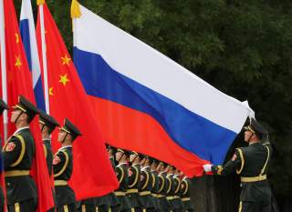 A military officer adjusts a Russian flag ahead of a welcome ceremony hosted by Chinese President Xi Jinping for Russian President Vladimir Putin outside the Great Hall of the People in Beijing, China June 8, 2018. REUTERS/Jason Lee