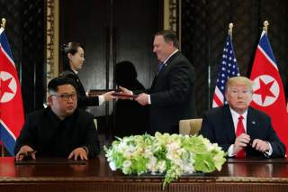 North Korea's leader Kim Jong Un looks at U.S. President Donald Trump as Kim's sister Kim Yo Jong exchanges document with U.S. Secretary of State Mike Pompeo at their summit at the Capella Hotel on Sentosa island in Singapore June 12, 2018. REUTERS/Jonath