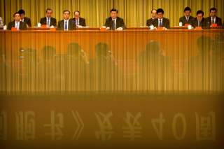 A banner is reflected on a polished surface as Chinese President Xi Jinping (C) speaks during an event to commemorate the 40th anniversary of the 