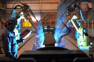 A worker stands next to robotic arms welding pump truck part at a factory of the Foton Loxa Heavy Machinery Co in Zhangjiakou, Hebei province, China May 24, 2019. REUTERS/Stringer 