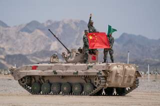 Chinese soldiers of People's Liberation Army (PLA) pose for photos with a Chinese national flag on a tank during the Suvorov Attack contest of the International Army Games 2019 in Korla, Xinjiang Uighur Autonomous Region, China August 4, 2019. Reuters