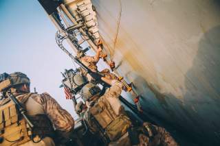 Marines with the Maritime Raid Force, 11th Marine Expeditionary Unit (MEU) climb a ladder to board the amphibious transport dock ship USS John P. Murtha (LPD 26) during a visit, board, search and seizure training exercise in the Gulf, in this undated