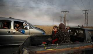 A woman with a baby sits at a back of a truck as they flee Ras al Ain town, Syria October 9, 2019. REUTERS/Rodi Said TPX IMAGES OF THE DAY