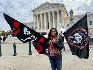 Christina Burnham holds pirate-themed flags in front of the Supreme Court in Washington November 5, 2019 in support of her uncle, Frederick Allen, a filmmaker whose appeal in a copyright lawsuit over the use of his footage of Blackbeard’s shipwreck is bei