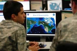 2Lt William Liggett (L) talks with a colleague as a map is displayed on one of the screens at the Air Force Space Command Network Operations & Security Center at Peterson Air Force Base in Colorado Springs, Colorado July 20, 2010. U.S. national security p