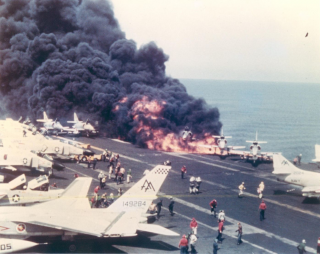 In the first moments of the U.S.S. Forrestal disaster, an A-4 Skyhawk burns immediately after its fuel tank is ruptured by a Zuni rocket. 29 July 1967. U.S. Navy.
