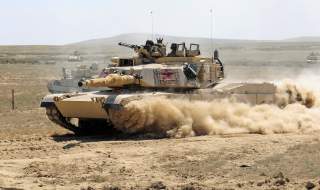 A U.S. Army M1A2 Abrams main battle tank assigned to the Minnesota National Guard races through a breach in a barbed wire obstacle during the 116th eXportable Combat Training Exercise at the Orchard Combat Training Center, Idaho, Aug. 21, 2014