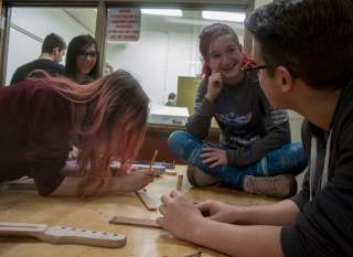 Students work together when they build guitars in class, reinforcing what they learn.  James Cordero, CC BY-SA