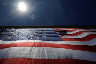 As 95-by-50-foot American flag is unfurled on the side of an apartment complex, a replica of the 