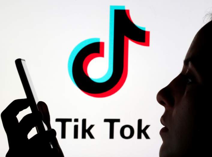 A person holds a smartphone as Tik Tok logo is displayed behind in this picture illustration taken November 7, 2019. Picture taken November 7, 2019. REUTERS/Dado Ruvic/Illustration