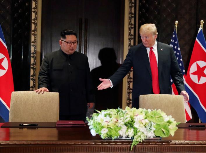 FILE PHOTO: U.S. President Donald Trump and North Korea's leader Kim Jong Un (L) arrive to sign a document to acknowledge the progress of the talks and pledge to keep momentum going, after their summit at the Capella Hotel on Sentosa island in Singapore, 