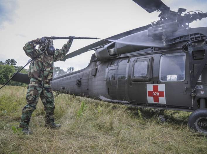 An Army Reserve Soldier assigned to the 308th Chemical Company, 450th Chemical Battalion, 209th Regional Support Group, 76th Operational Response Command sprays water on a "contaminated" Blackhawk helicopter during a decontamination operation
