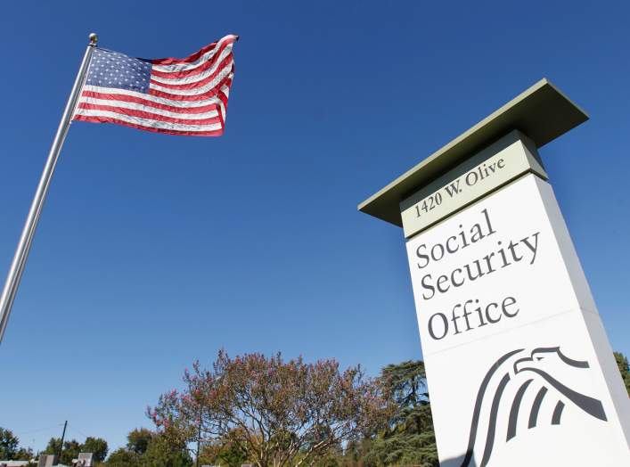 An American flag flutters in the wind next to signage for a United States Social Security Administration office in Burbank, California October 25, 2012. REUTERS/Fred Prouser