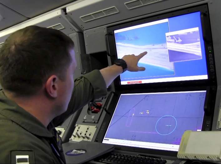 A U.S. Navy crewman aboard a P-8A Poseidon surveillance aircraft views a computer screen purportedly showing Chinese construction on the reclaimed land of Fiery Cross Reef in the disputed Spratly Islands in the South China Sea in this still image from vid