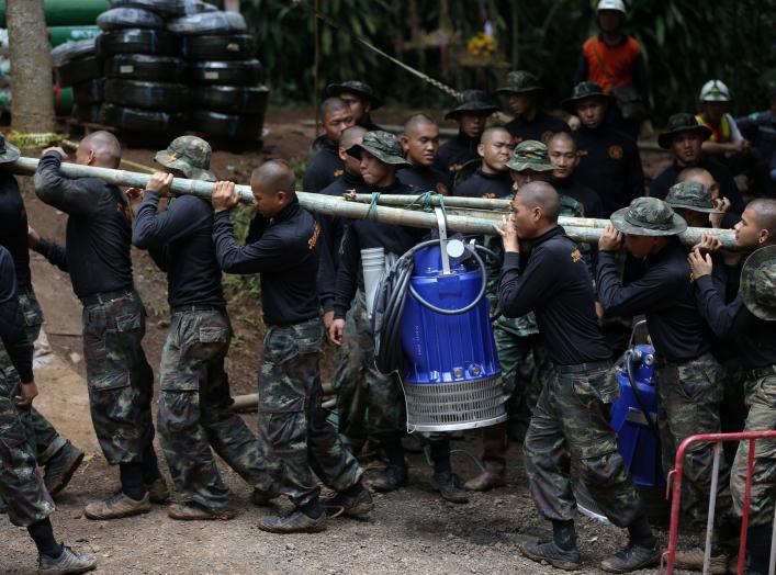 Military personnel carry a water pump machine as they enter the Tham Luang cave complex, where 12 boys and their soccer coach are trapped, in the northern province of Chiang Rai, Thailand, July 6, 2018. REUTERS/Athit Perawongmetha