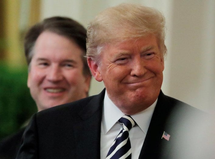 U.S. President Donald Trump smiles next to U.S. Supreme Court Associate Justice Brett Kavanaugh as they participate in a ceremonial public swearing-in in the East Room of the White House in Washington, U.S., October 8, 2018. REUTERS/Jim Bourg