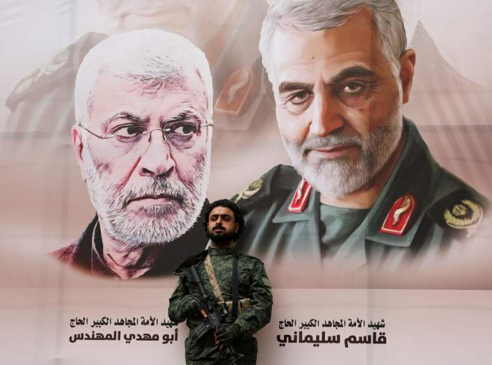 A Houthi militant stands by a billboard with posters of Iraqi militia commander Abu Mahdi al-Muhandis and Iranian military commander Qassem Soleimani during a rally by Houthi supporters to denounce the U.S. killing of both commanders, in Sanaa, Yemen