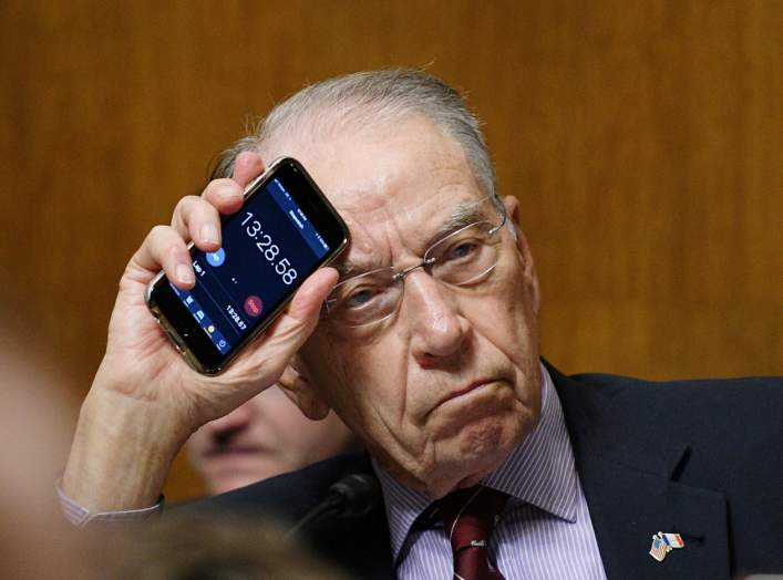 Senator Chuck Grassley, R-IA, Chairman holds up the timer on his phone while Senator Cory Booker, D-NJ makes an impassioned speech during the Senate Judiciary Committee meeting to vote on the nomination of Brett Kavanaugh to be an associate justice